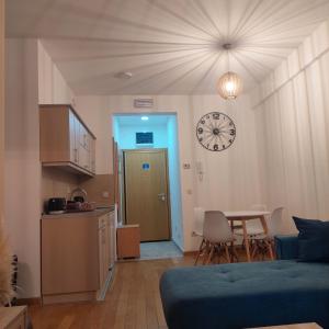 a living room with a table and a clock on the wall at Apartman Ana Alibi 1 in Zlatibor