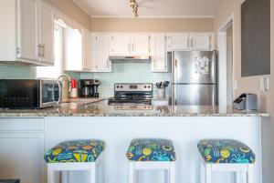 a kitchen with white cabinets and a stainless steel refrigerator at Large Oceanfront condo in a quiet section of Carolina Beach Rentals in Carolina Beach