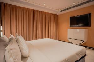 Bur'Dera - a Boutique Luxury Hotel في جايبور: غرفة نوم مع سرير أبيض كبير مع تلفزيون بشاشة مسطحة