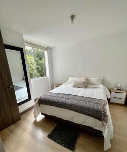 a white bedroom with a bed and a large window at Sabaneta 22 in Sabaneta