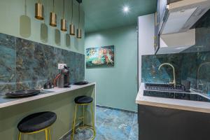 uma cozinha com um lavatório e um balcão com bancos em Le Musée d’Aphrodite / JACUZZI em Montgeron