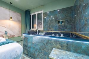 een badkamer met een groot bad en een spiegel bij Le Musée d’Aphrodite / JACUZZI in Montgeron