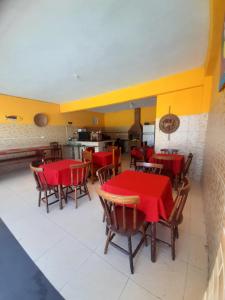 uma sala de jantar com mesas vermelhas e cadeiras de madeira em Pousada Canaã em Tamandaré