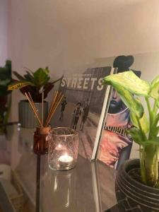 a table with a book and a candle and plants at Spitalfields Market Penthouse Flat with balcony in London