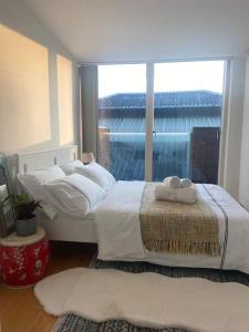 two beds in a room with a large window at Spitalfields Market Penthouse Flat with balcony in London