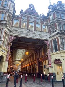 un hombre parado frente a un gran edificio en Spitalfields Market Penthouse Flat with balcony, en Londres