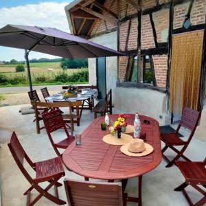 Montpont-en-Bresse的住宿－La Grange à outeaux，庭院里配有一张带椅子和遮阳伞的木桌
