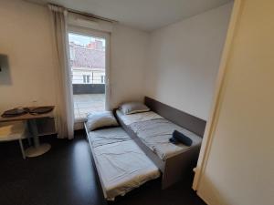 um pequeno quarto com uma cama e uma janela em Le Stratège em Marselha