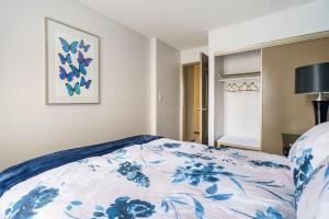 a bedroom with a bed with a blue and white blanket at Entire Condo Downtown, near BMO & Saddle Dome, free Parking, 1,5 hrs to Banff in Calgary