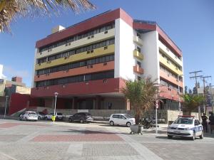 a large building with cars parked in a parking lot at Farol Barra Flat completo e bem localizado in Salvador