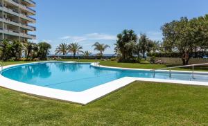 a swimming pool in a resort with grass and trees at Front sea view apartment on Marbella's beach promenade in Marbella
