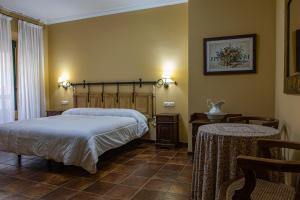 Perales del Puerto的住宿－DON JULIO，一间卧室配有一张床、一张桌子和两把椅子