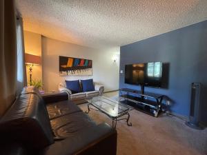 uma sala de estar com um sofá e uma televisão de ecrã plano em Entire Condo Downtown, near BMO & Saddle Dome, free Parking, 1,5 hrs to Banff em Calgary