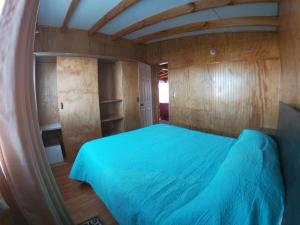 Schlafzimmer mit blauem Bett und Holzwänden in der Unterkunft Cabañas Rayen Karu in Puerto Montt