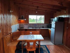 a kitchen with a table and a refrigerator at Cabañas Rayen Karu in Puerto Montt