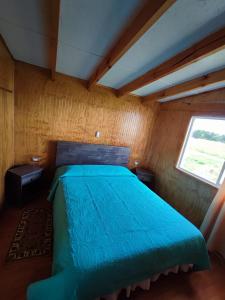 a bedroom with a blue bed with a window at Cabañas Rayen Karu in Puerto Montt