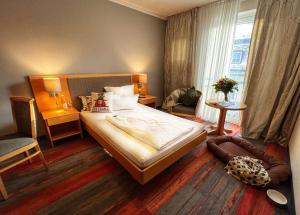 ein Schlafzimmer mit einem Bett, einem Stuhl und einem Fenster in der Unterkunft Hotel Prinz in München