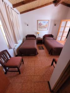 a bedroom with two beds and a chair at Hotel Diego de Almagro San Pedro De Atacama in San Pedro de Atacama