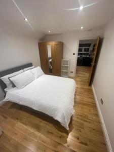 a bedroom with a white bed and a wooden floor at 2 bedroom apartment in HampdenRd in London