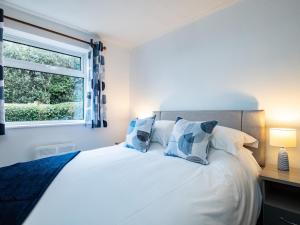 a bedroom with a bed with blue and white pillows at Shorelands in Wadebridge