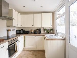 a kitchen with white cabinets and a sink and a window at 6 Erasmus Street in Penmaen-mawr