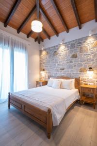 a bedroom with a large bed and a stone wall at Amigdalies in Myrina