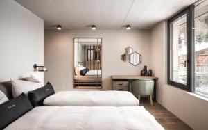 two beds in a bedroom with a desk and a mirror at Avita Loft by Avita suites to relax in Santa Cristina in Val Gardena