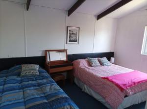a bedroom with two beds and a mirror and a table at Hotel Estación Náutica - Aeropuerto in Punta Arenas