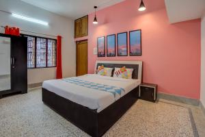 a bedroom with a large bed and a pink wall at OYO Home Jaam's Home Stay in Bhubaneshwar