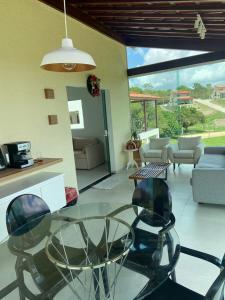 a living room with a glass table and chairs at CASA TOTALMENTE EQUIPADA AMPLA E CONFORTAVEL em CONDOMINIO - CHÃ GRANDE-PE in Chã Grande