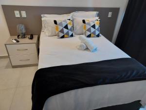 un letto con 2 cuscini e una coperta bianca e nera di Flat América Pelinca Campos a Campos dos Goytacazes