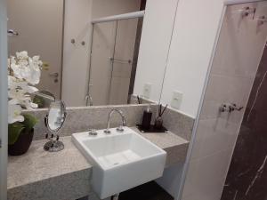 W łazience znajduje się biała umywalka i lustro. w obiekcie Flat América Pelinca Campos w mieście Campos dos Goytacazes