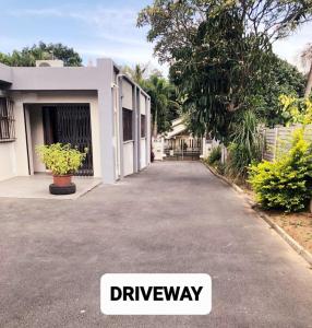 a driveway in front of a white house at The Prayer and Family Guesthouse in Durban