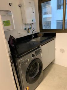a kitchen with a washing machine and a sink at Apto novo a uma quadra da praia in Florianópolis