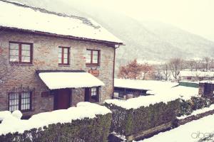 a stone house with snow on the roof at Casa Rural Bango in Caboalles de Abajo