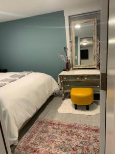 a bedroom with a bed and a mirror and a yellow stool at Comfy and Chic Boston Apartment! in Boston
