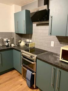 a kitchen with green cabinets and a stove top oven at City Central 2 Bedroom Apartment in Chester