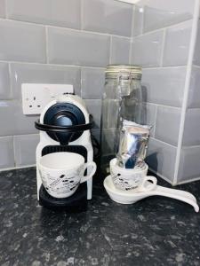 a coffee maker and two cups on a counter at City Central 2 Bedroom Apartment in Chester