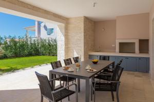 kuchnia i jadalnia ze stołem i krzesłami w obiekcie Villa Harmony by ILC (Istria Luxury Collection) w mieście Brtonigla