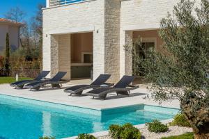 szereg leżaków przy basenie w obiekcie Villa Harmony by ILC (Istria Luxury Collection) w mieście Brtonigla