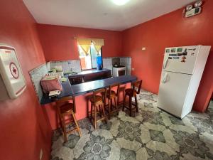 cocina con paredes rojas, mesa y nevera en Casa de Lewis, en Puerto Baquerizo Moreno