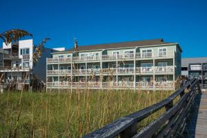 a building on the beach with a wooden fence at Sands IV 2-G in Carolina Beach