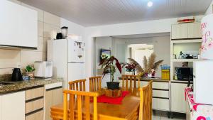 cocina con mesa de madera y nevera blanca en Para desfutar com a familia, en Bombinhas