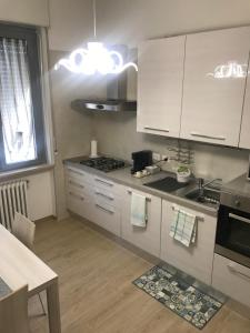 a kitchen with white cabinets and a sink and a table at Cà Nicola 3 in Cortemaggiore