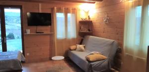 - un salon avec un canapé, des oreillers et une télévision dans l'établissement Le chalet de Pierrot, à La Malène