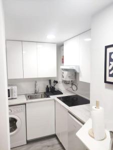 een witte keuken met een wastafel en een vaatwasser bij Acogedor apartamento familiar en área residencial in Madrid
