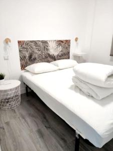 a white bed with white pillows on top of it at Acogedor apartamento familiar en área residencial in Madrid