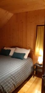 - une chambre avec un lit dans une pièce dotée de murs en bois dans l'établissement Le chalet de Pierrot, à La Malène