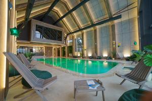 a swimming pool with two chairs and a table at Hedonist Zlatibor Mountain Wellness & SPA in Zlatibor