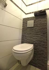 a white toilet in a bathroom with a brick wall at WRN APARTAMENTY in Kalisz